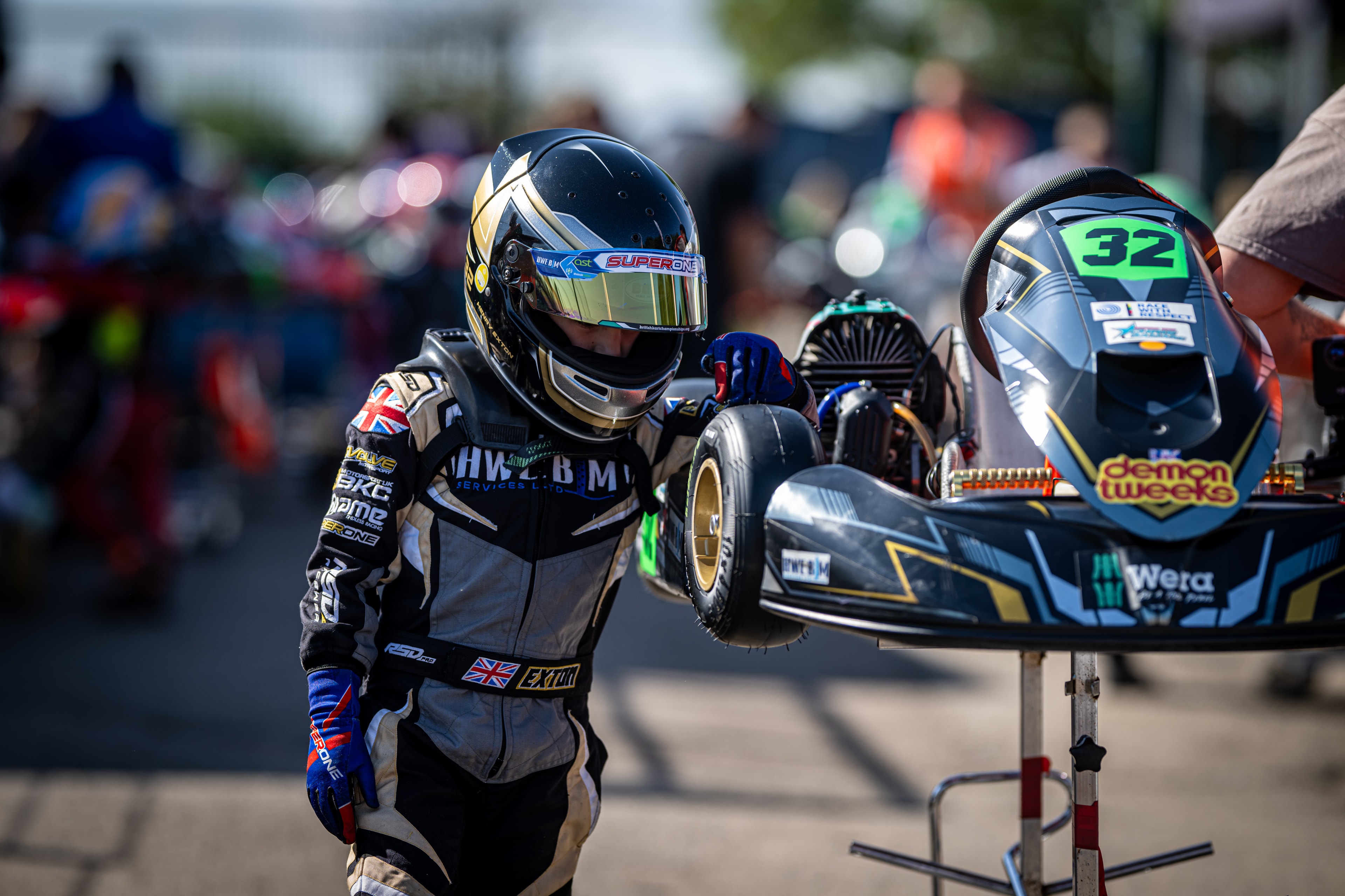 Henry Exton with helmet on inspecting kart number 32 in the paddock at Whilton Mill